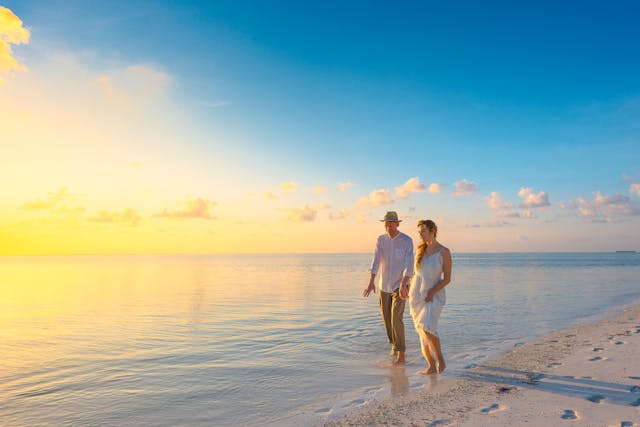 two people walking on a beach an sunset