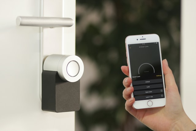 person holding up their phone to show a smart lock system connected to their home security