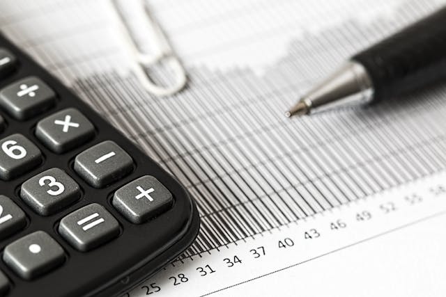 a calculator and a pen resting on a spread sheet