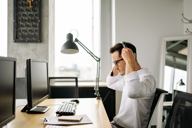 a person putting on a headset while sitting at their desk