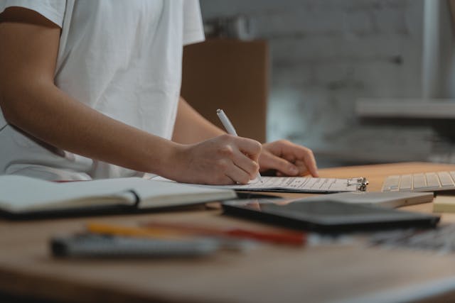 a person using a pen and writing on a clipboard