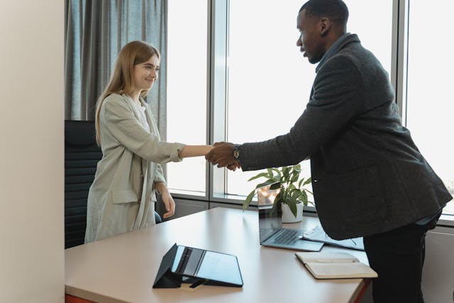 two people shaking hands across a desk