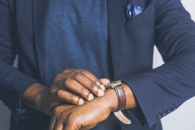 person in a dark blue suit checking their watch
