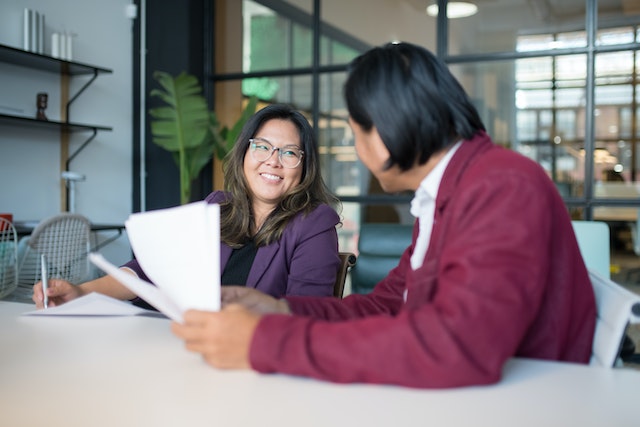 property manager in purple jacket smiling at colleague in a mauve jacket