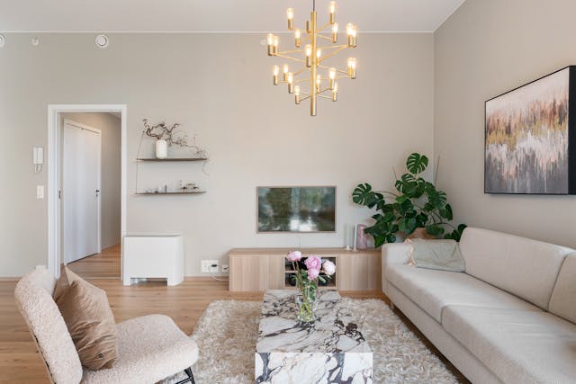 a beige living room with light food floors and a white couch