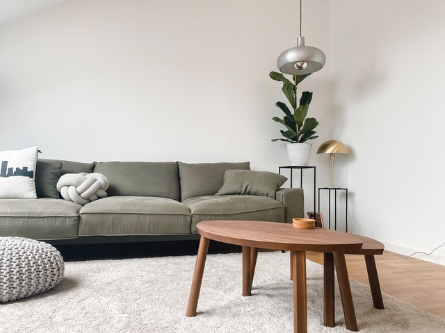 a green couch and wooden coffee table in a white living room