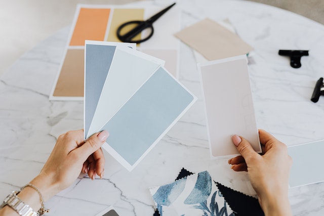person holding a bunch of blue, white and beige paint swatches