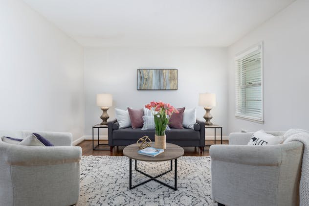 a white living room with a dark grey couch and two light grey chairs