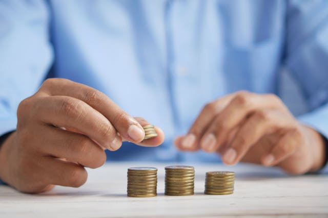 a person stacking coins in three piles
