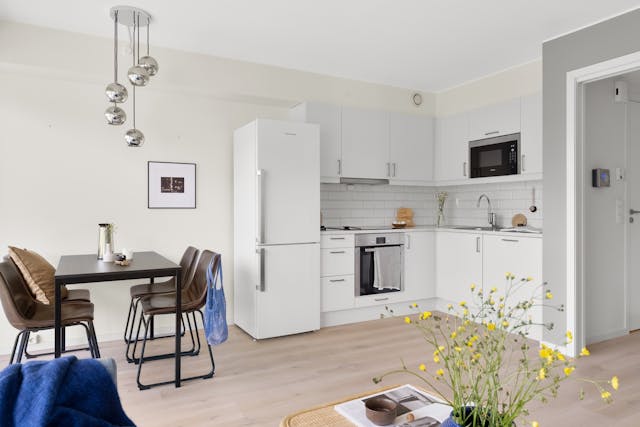 a white kitchen a small table with brown chairs